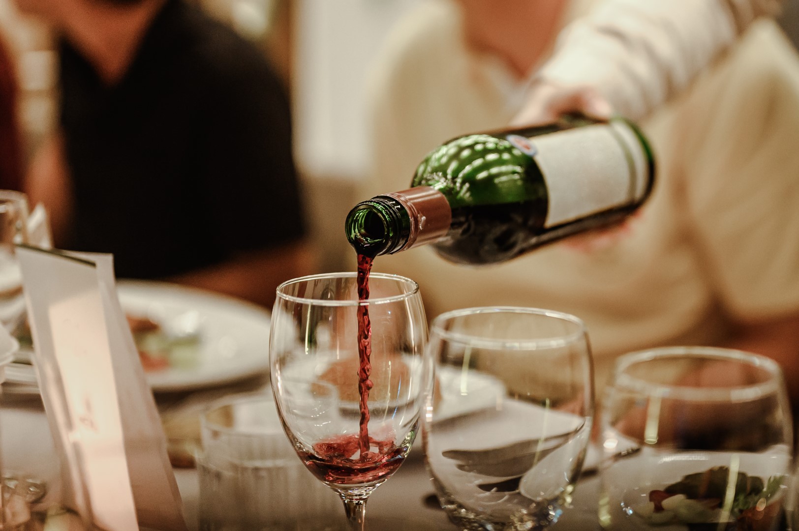 Red wine being poured into a glass at dinner